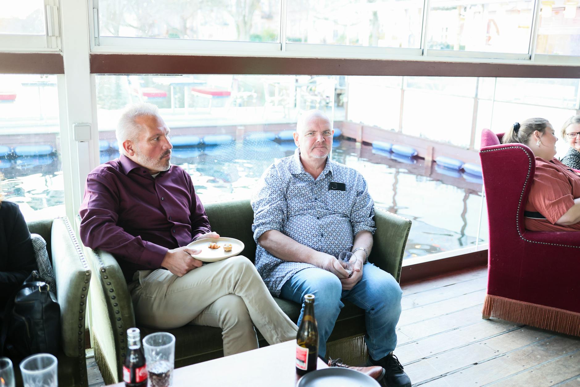 Dwóch mężczyzn przy stoliku w przytulnej kawiarni z widokiem na wodę