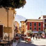 Ludzie w słonecznej włoskiej uliczce siedzący w kawiarniach na zewnątrz