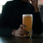 Regionalne smaki pod Lanckoroną: karczmy, zajazdy i domowa kuchnia Kobieta przy barze trzyma piwo, obok talerz z chipsami