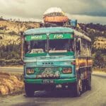 Pociągiem i busem w okolice Lanckorony: jak dojechać bez auta i nie utknąć Kolorowy zabytkowy autobus jedzie wiejską drogą pod pochmurnym niebem