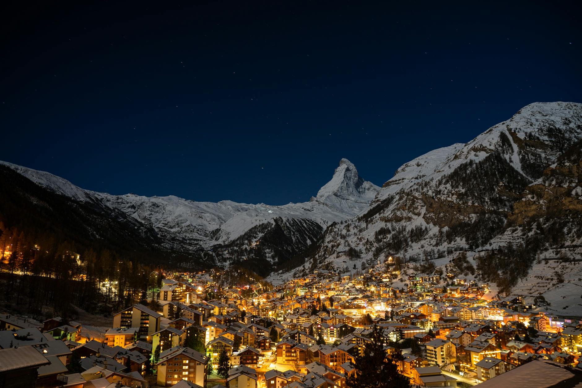 Nocny widok alpejskiego miasteczka z oświetlonym szczytem Matterhorn