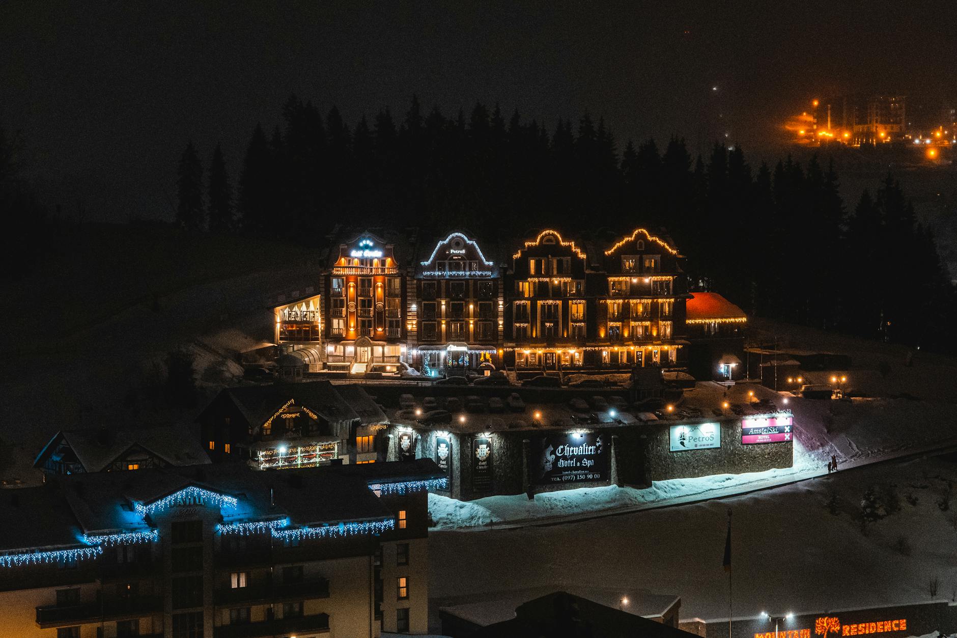 Zimowy górski kurort nocą z oświetlonymi domami i zaśnieżonymi stokami