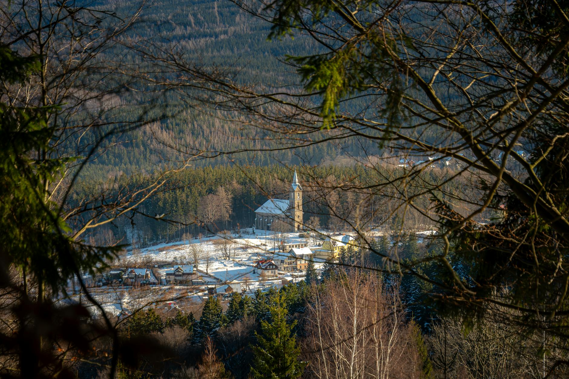 Zimowy krajobraz górski z kościołem na tle ośnieżonego lasu