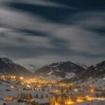 Zimowy nocny widok górskiej wioski oświetlonej ciepłymi światłami