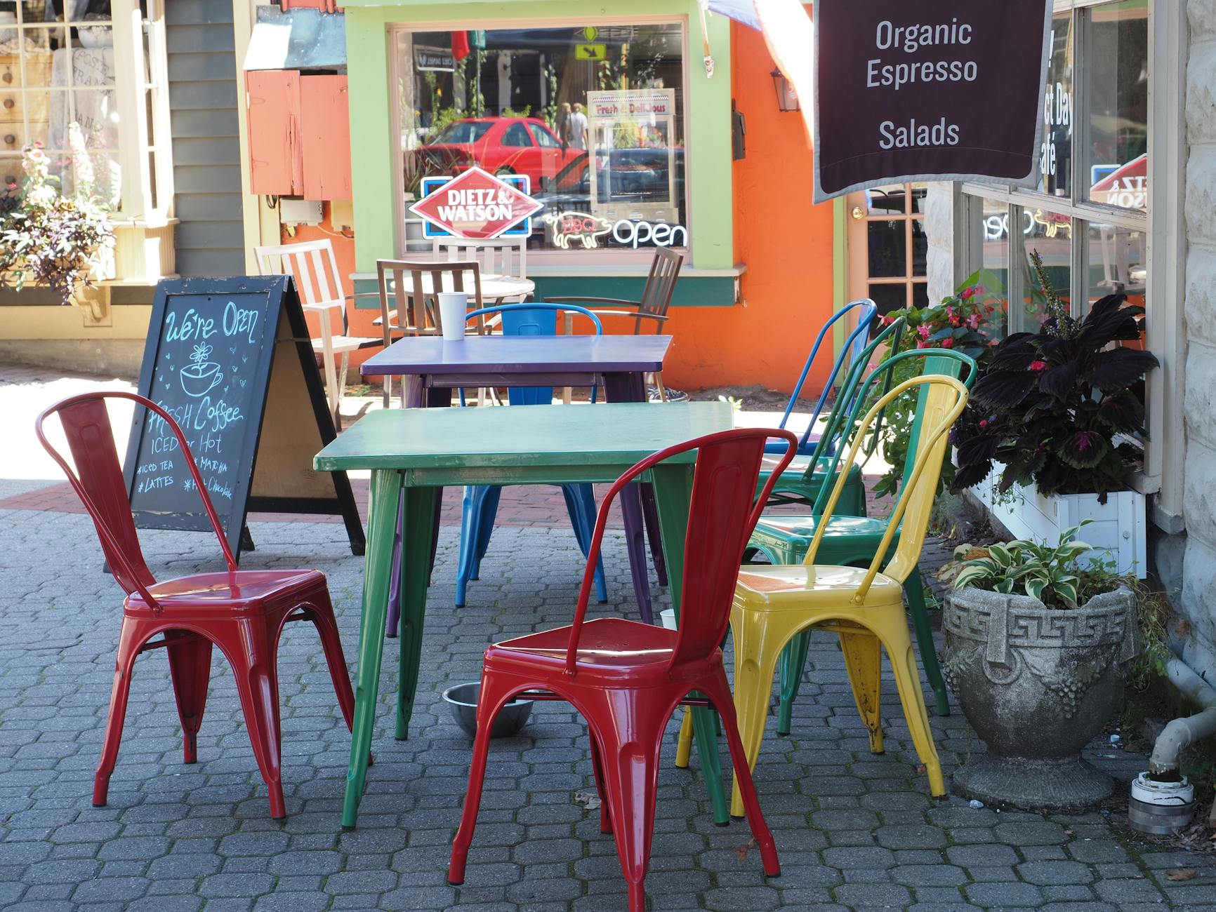 Kolorowe stoliki i krzesła w zewnętrznej kawiarni w słoneczny dzień