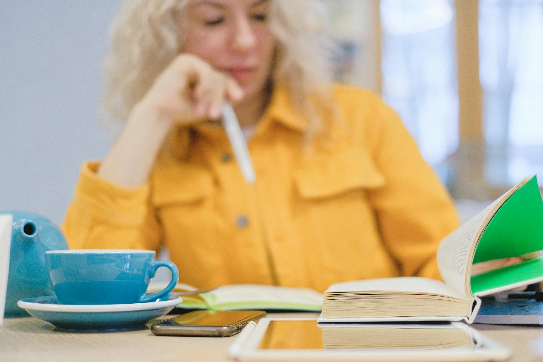 Studentka uczy się przy kawie z książkami i tabletem w przytulnym wnętrzu