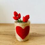 Czerwone tulipany w ręcznie robionym ceramicznym wazonie z sercem na biurku