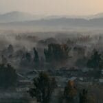 Poranek we mgle nad górską wioską z widokiem na odległe szczyty