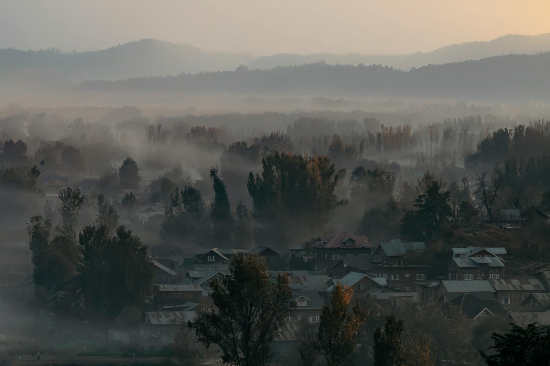 Poranek we mgle nad górską wioską z widokiem na odległe szczyty