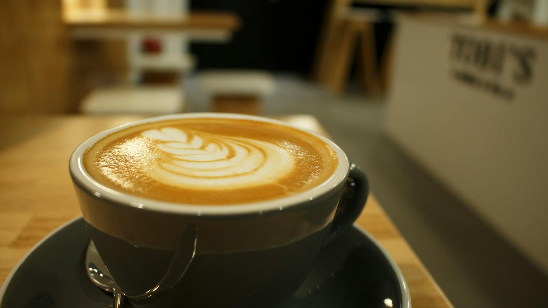 Cappuccino z latte art na drewnianym stoliku w przytulnej kawiarni