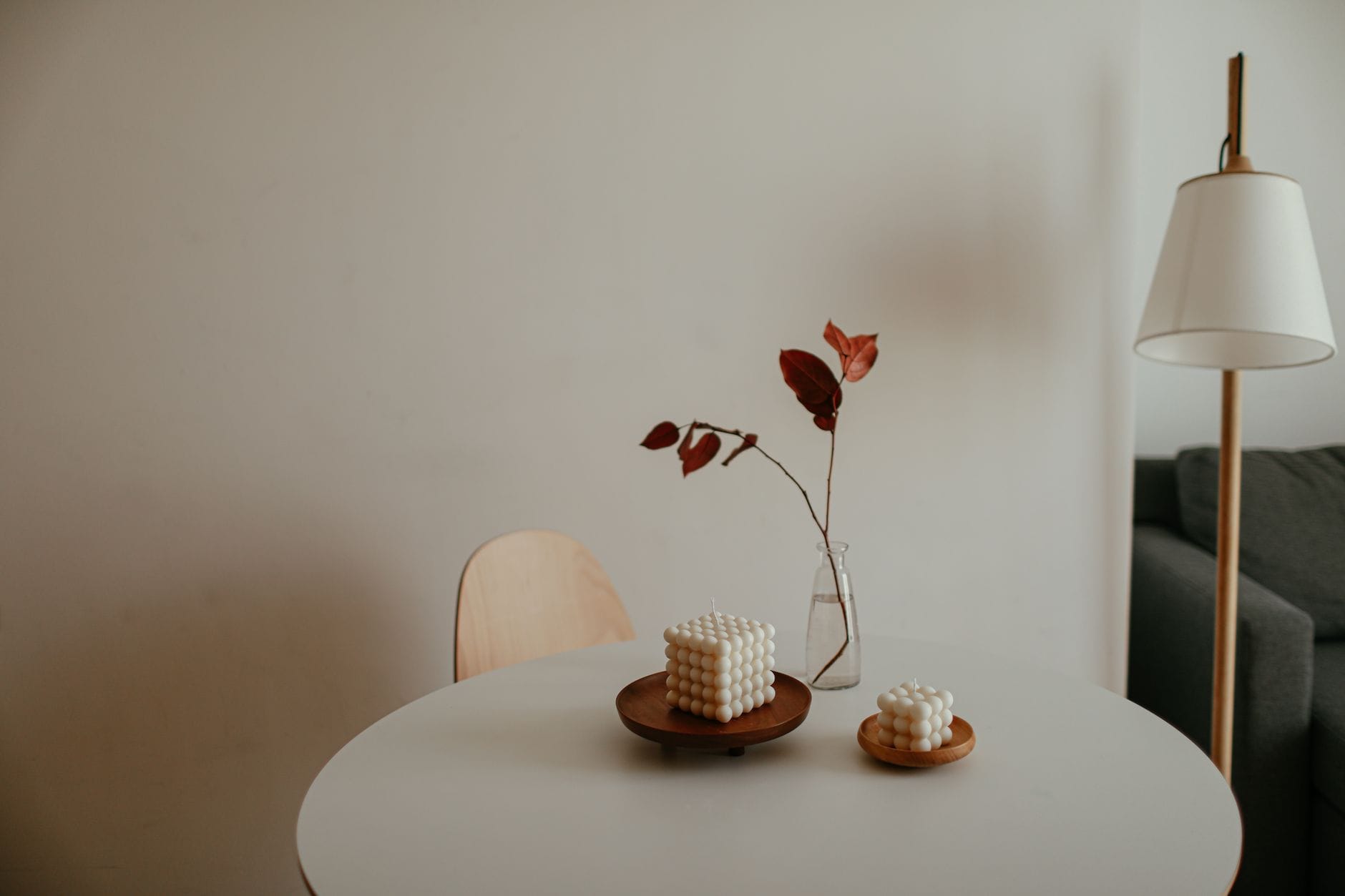 Minimalistyczny salon z palącymi się świecami na stole i lampą w tle